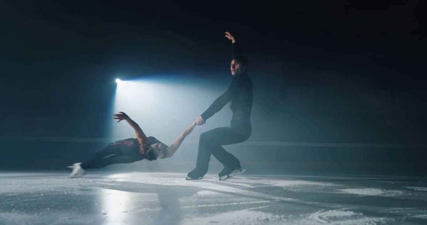 电影近距离拍摄的年轻夫妇艺术花样滑冰表演双人滑冰舞蹈比赛开始前的溜冰场。完美，精确，自由，激情的理念视频素材