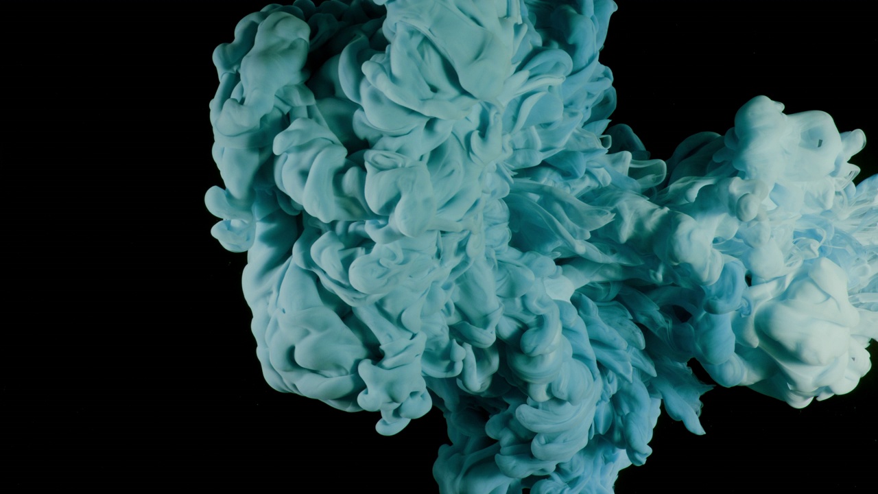 近距离和慢动作的墨在不同深浅的蓝绿色和蓝色飞溅和相互作用的水，并蔓延到整个框架上的黑色背景视频下载