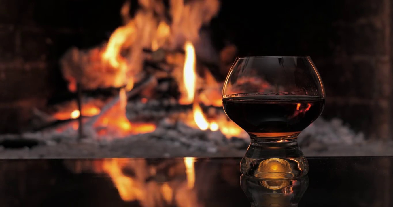 玻璃和白兰地在壁炉的火的背景上视频下载