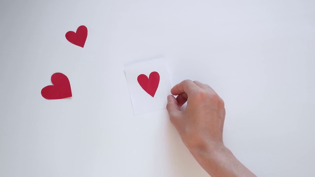 女人的手拿着小红纸心，在白色的背景上。国际妇女节视频下载