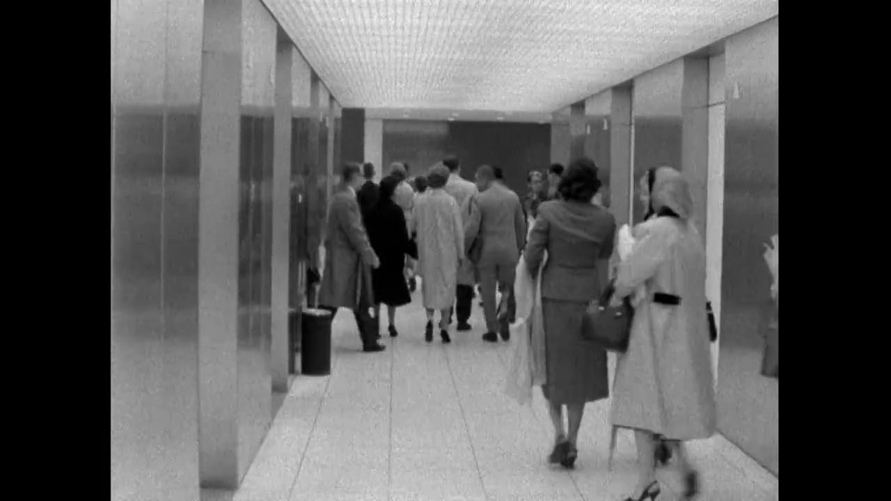 在纽约的一间办公室里，男男女女成群结队地走出电梯;1961视频素材