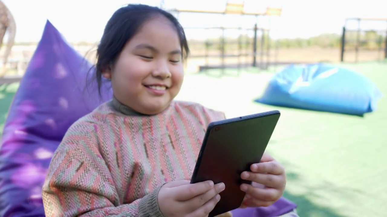 亚洲小女孩在公园用平板电脑看电影视频素材