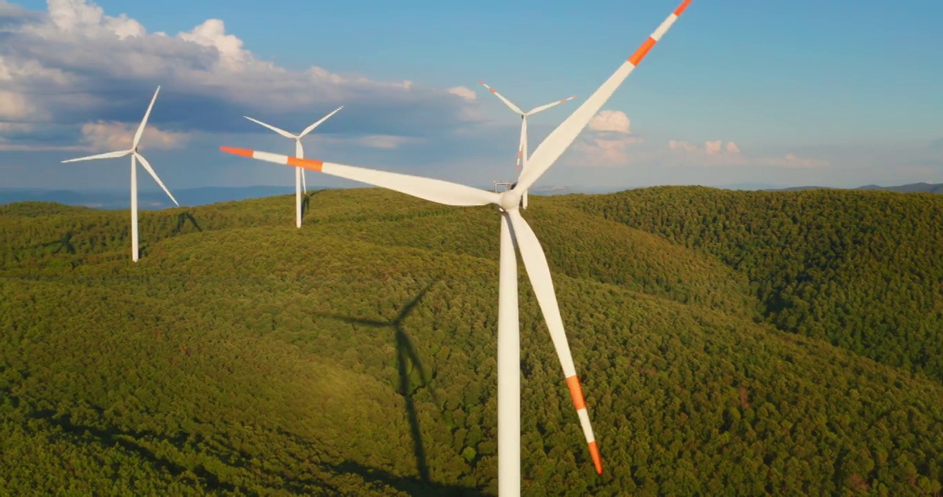 空中特写镜头风力磨坊旋转的力量，并产生可再生能源在绿色生态的方式，以太阳照耀地球。视频素材