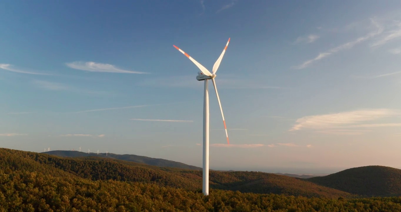 空中特写镜头，风力磨坊旋转的力量，风力和产生可再生能源的绿色生态方式，以地球上的日落。视频素材