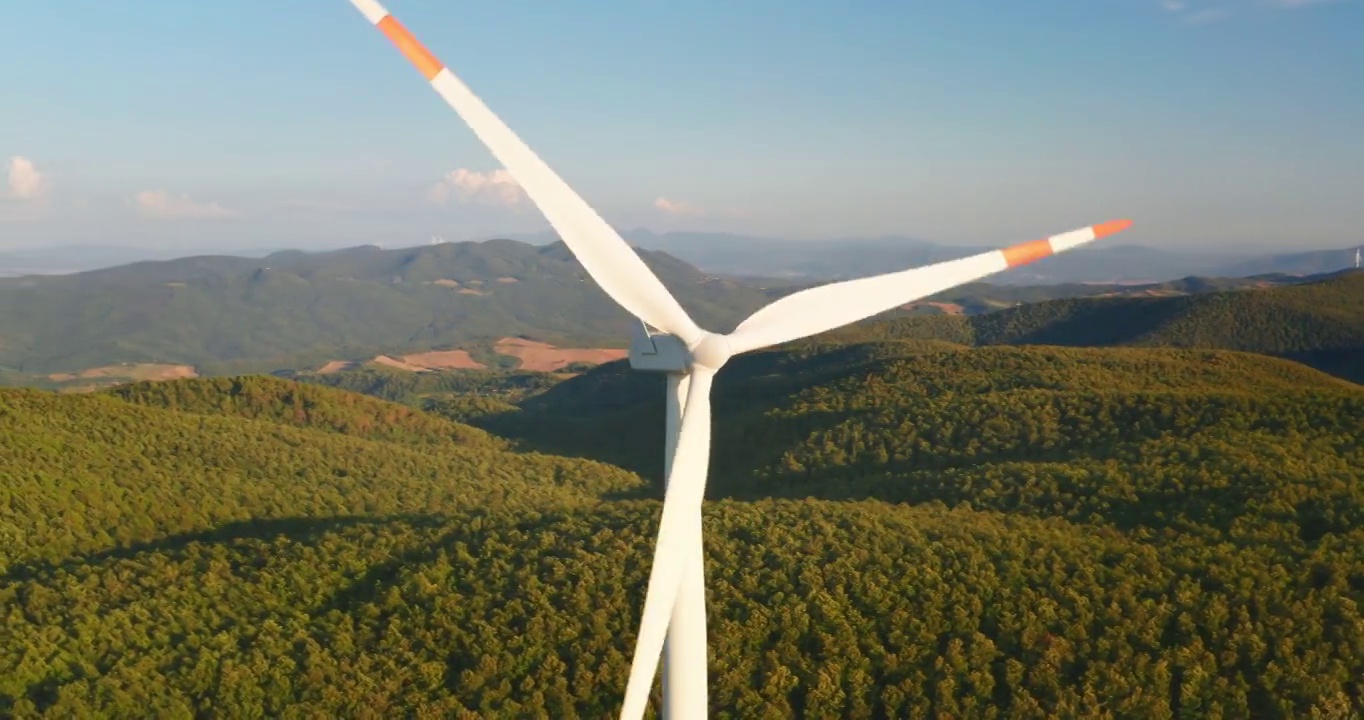 空中特写镜头风力磨坊旋转的力量，并产生可再生能源在绿色生态的方式，以太阳照耀地球。视频素材