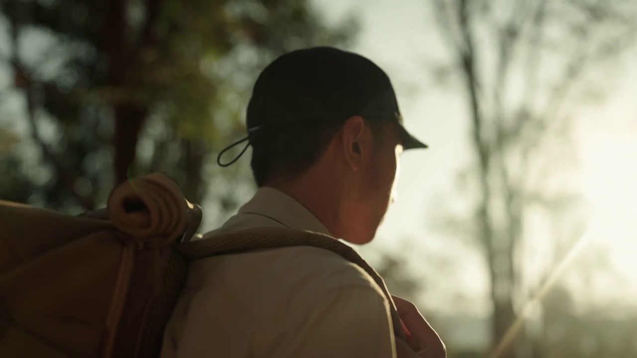 男子在假日里背着背包在树林里徒步旅行。视频购买