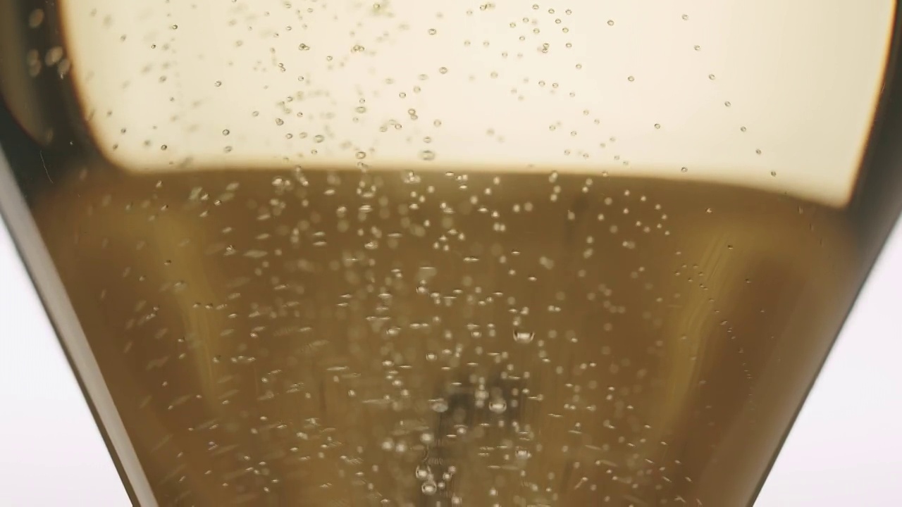 香槟酒倒进一个优雅的玻璃杯，白色底色，气泡视频素材