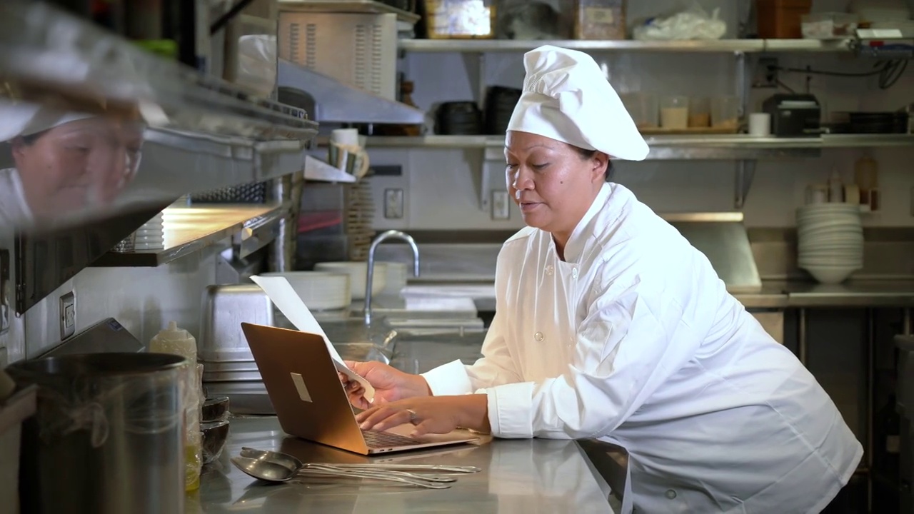 女厨师在商业厨房使用笔记本电脑视频下载