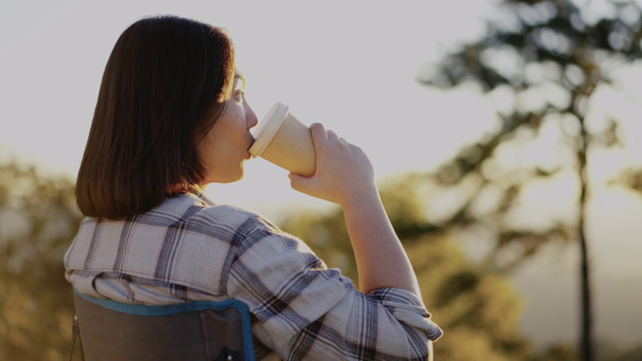 清晨，女人在户外的山上拿着咖啡杯放松视频素材