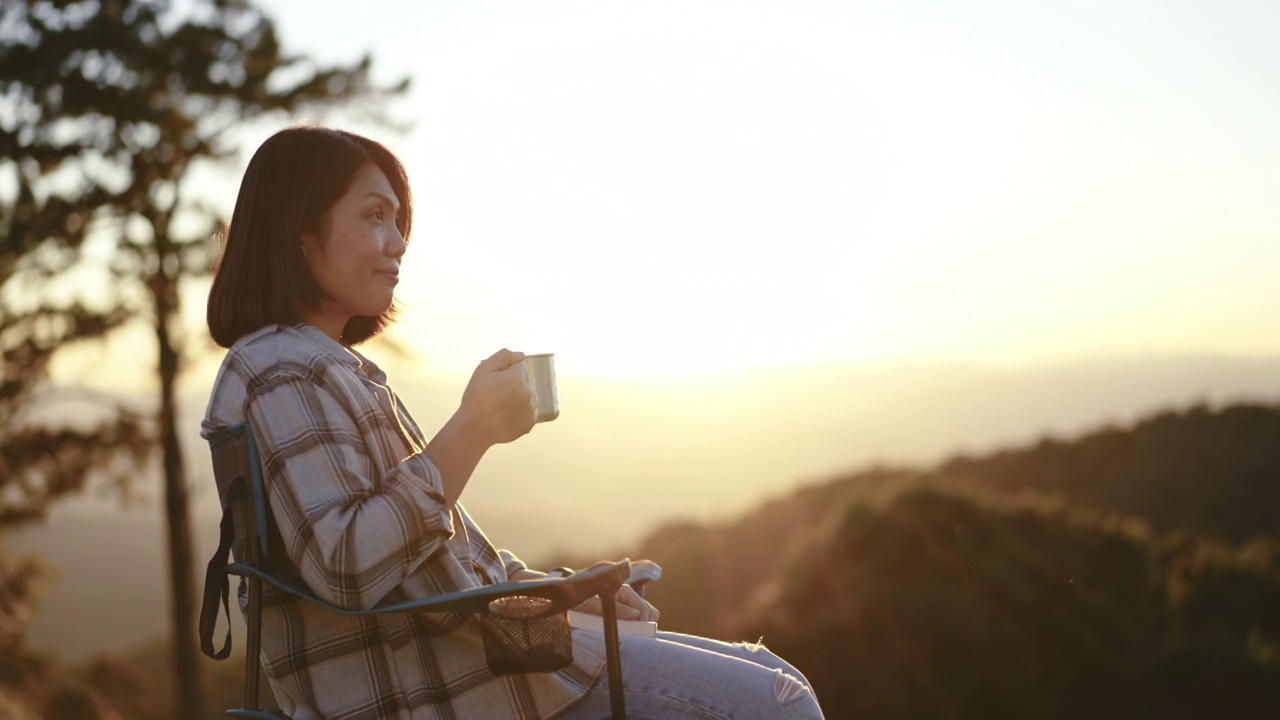 清晨，女人在户外的山上拿着咖啡杯放松视频下载