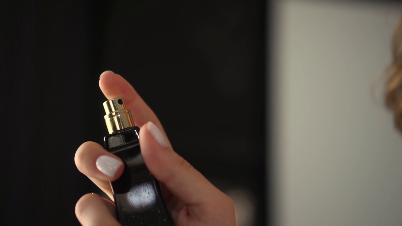 一个女人把香水拿在手里洒在身上视频素材