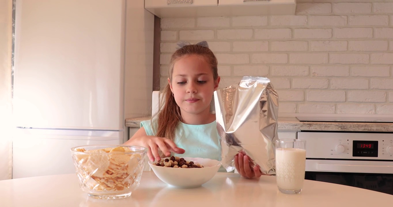在厨房吃早餐。婴儿吃早餐。这个女孩边吃麦片边喝牛奶。有用的孩子的早餐视频素材