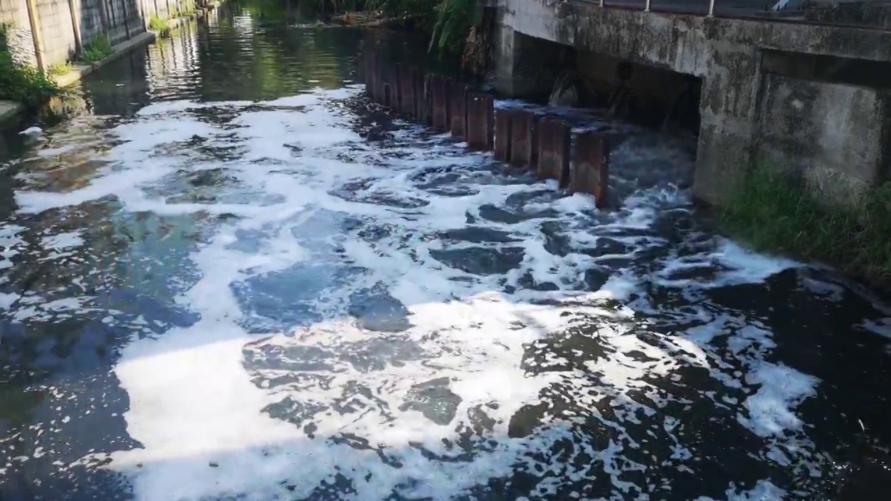 污水带着气泡泡沫流入污水河，污水来自城市，造成水污染，环境污染。排水系统防洪。环境保护视频素材