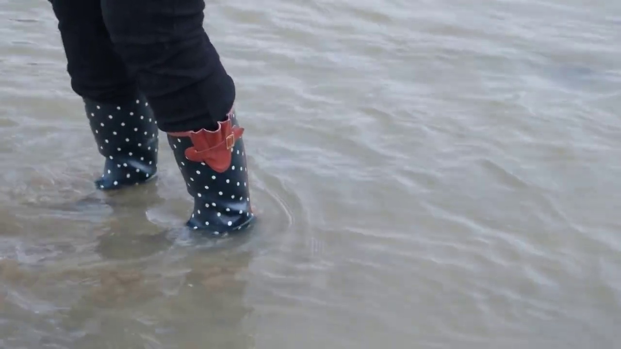 一个穿着胶靴的人站在河里。视频下载