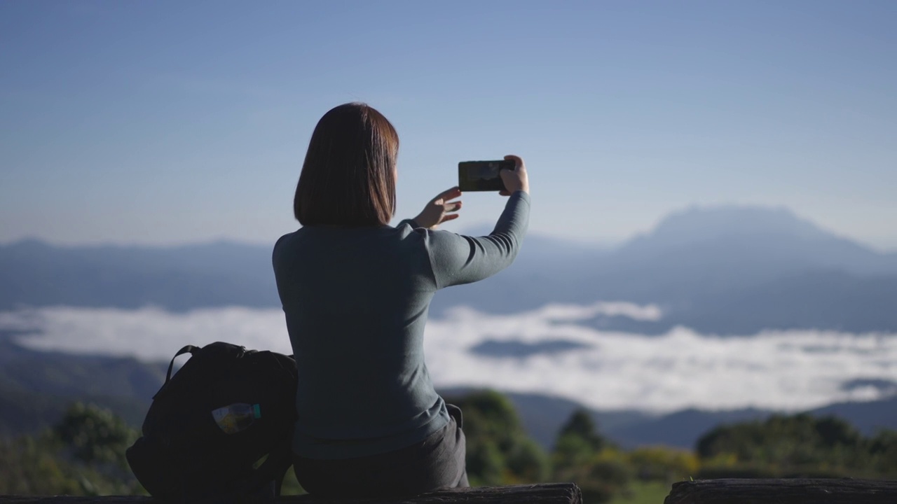 女旅行者在日出的时候在山上拍了一张美丽的照片视频素材