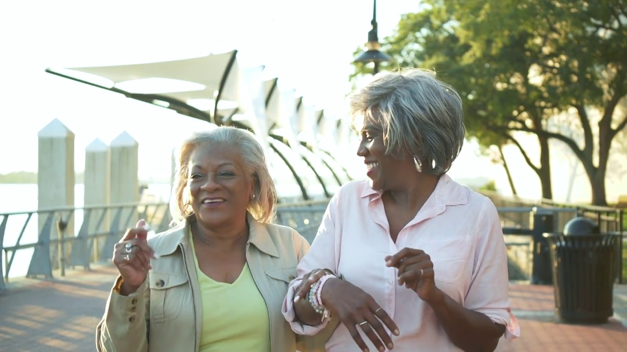 年长的非裔美国妇女走在城市海滨视频下载