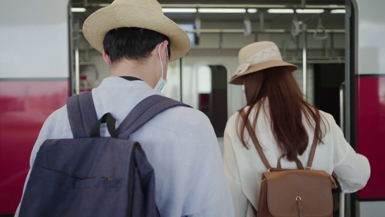 亚洲夫妇带着旅行行李，在抵达机场后坐地铁前往酒店。视频素材