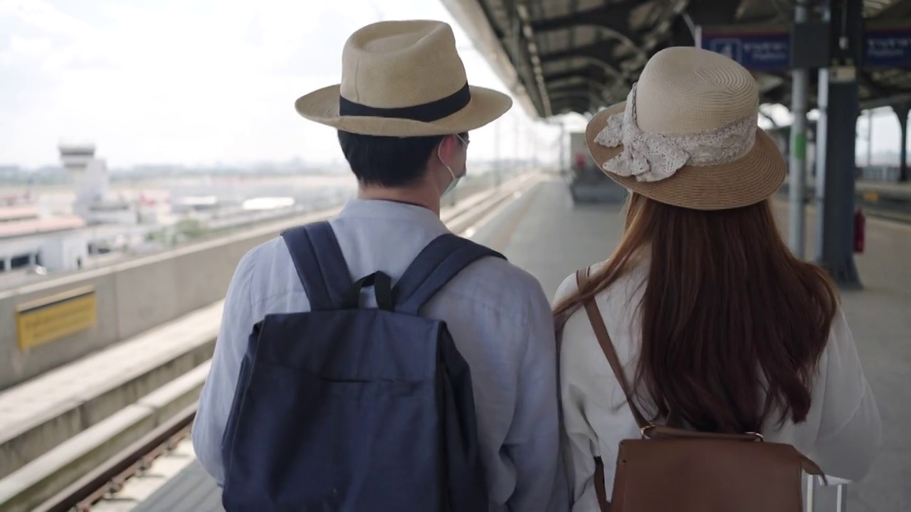 站台候车情侣——戴着医用口罩的美女和帅哥在疫情期间散步旅行——新常态生活理念视频素材