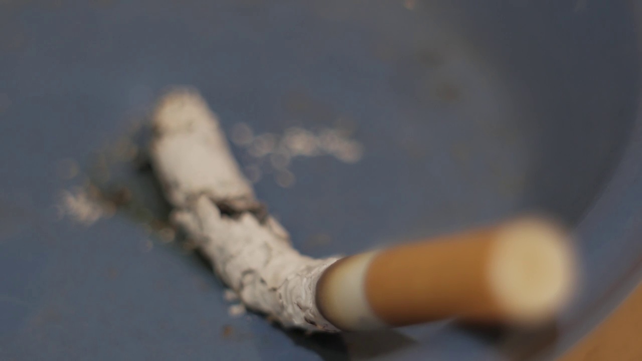 蓝色烟灰缸上的香烟熄灭了视频素材