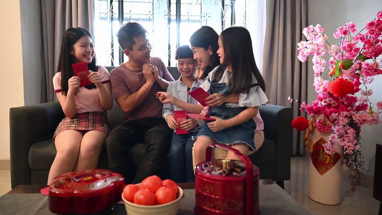 快乐的亚洲父母在中国新年的第一天给他们的孩子红包(Angpow)视频素材