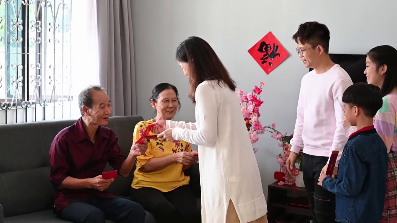 中国农历新年的第一天，亚洲老人在家里给他们的孩子和孙子孙女发红包。视频素材