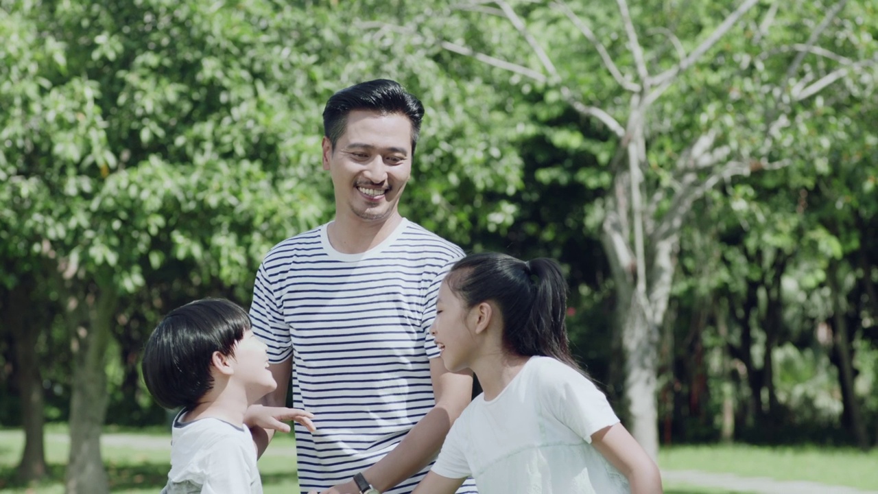 一位亚裔父亲在公园里和孩子们玩的时候把他的儿子抱起来视频素材