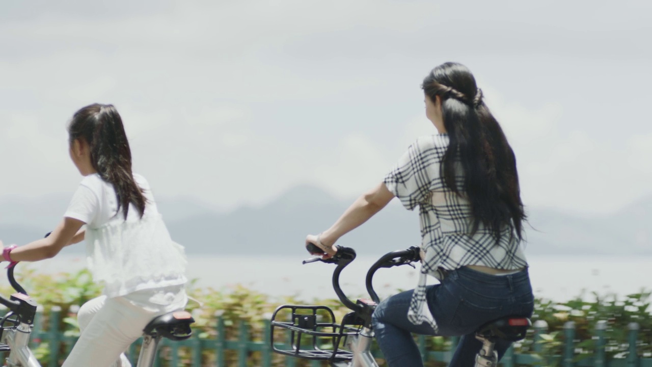 夏季，亚洲母女在海滨散步道上骑自行车视频下载