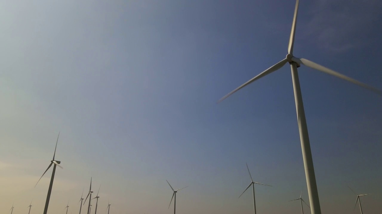 蓝天下旋转的风力涡轮机，风力发电技术视频素材