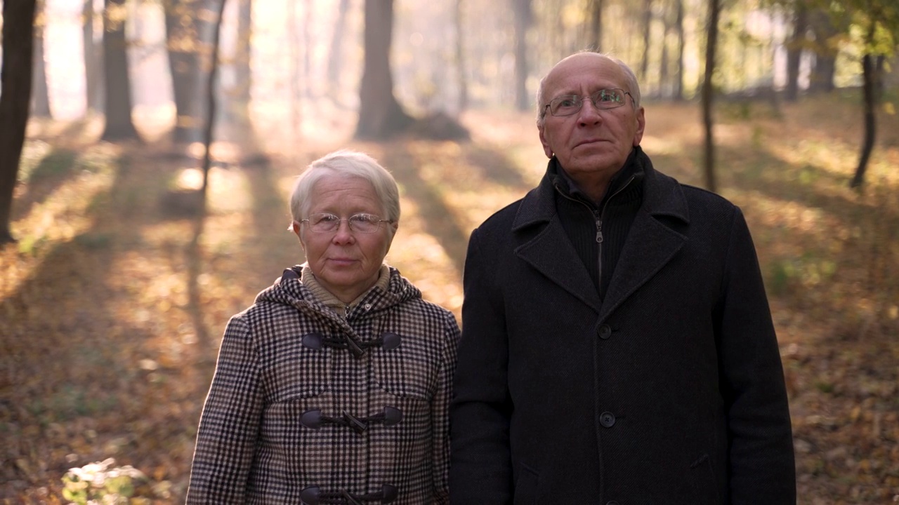 老夫妇在秋季公园散步时摆姿势视频下载
