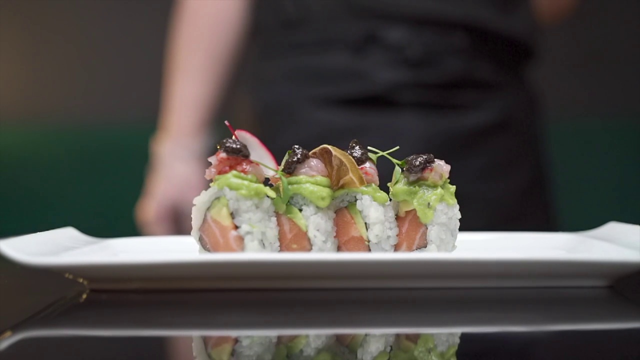 厨师将一盘日本生鱼片卷放在桌上视频素材