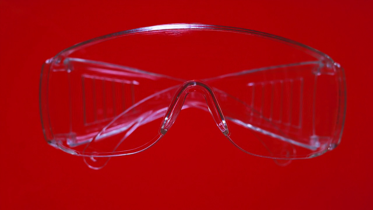 在鲜艳的红色和绿色背景上的保护眼镜。健康安全理念。塑料安全眼镜。个人防护设备。塑料护目镜，透明眼镜视频下载