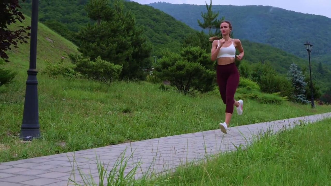 女运动员在风景优美的绿色公园慢跑视频素材