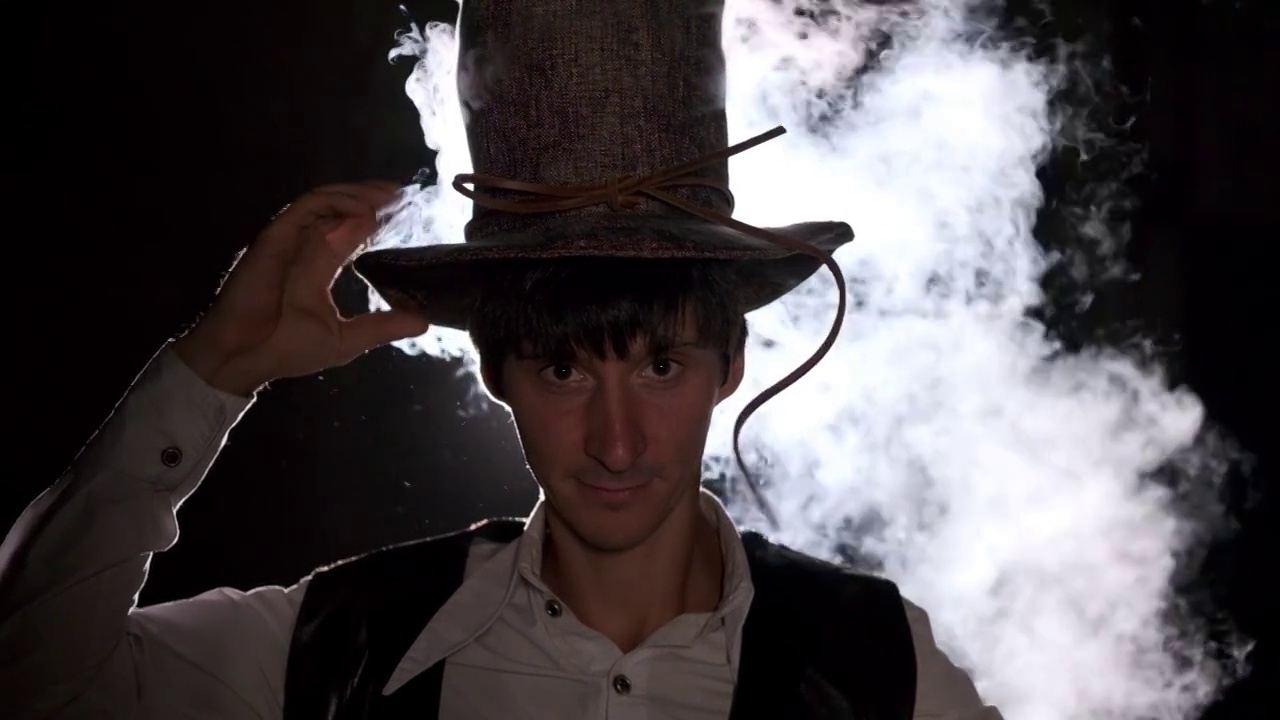 一个男炼金术士把一顶帽子戴在头上。蒸汽从帽子里冒出来。炼金术,魔法,神秘主义视频下载