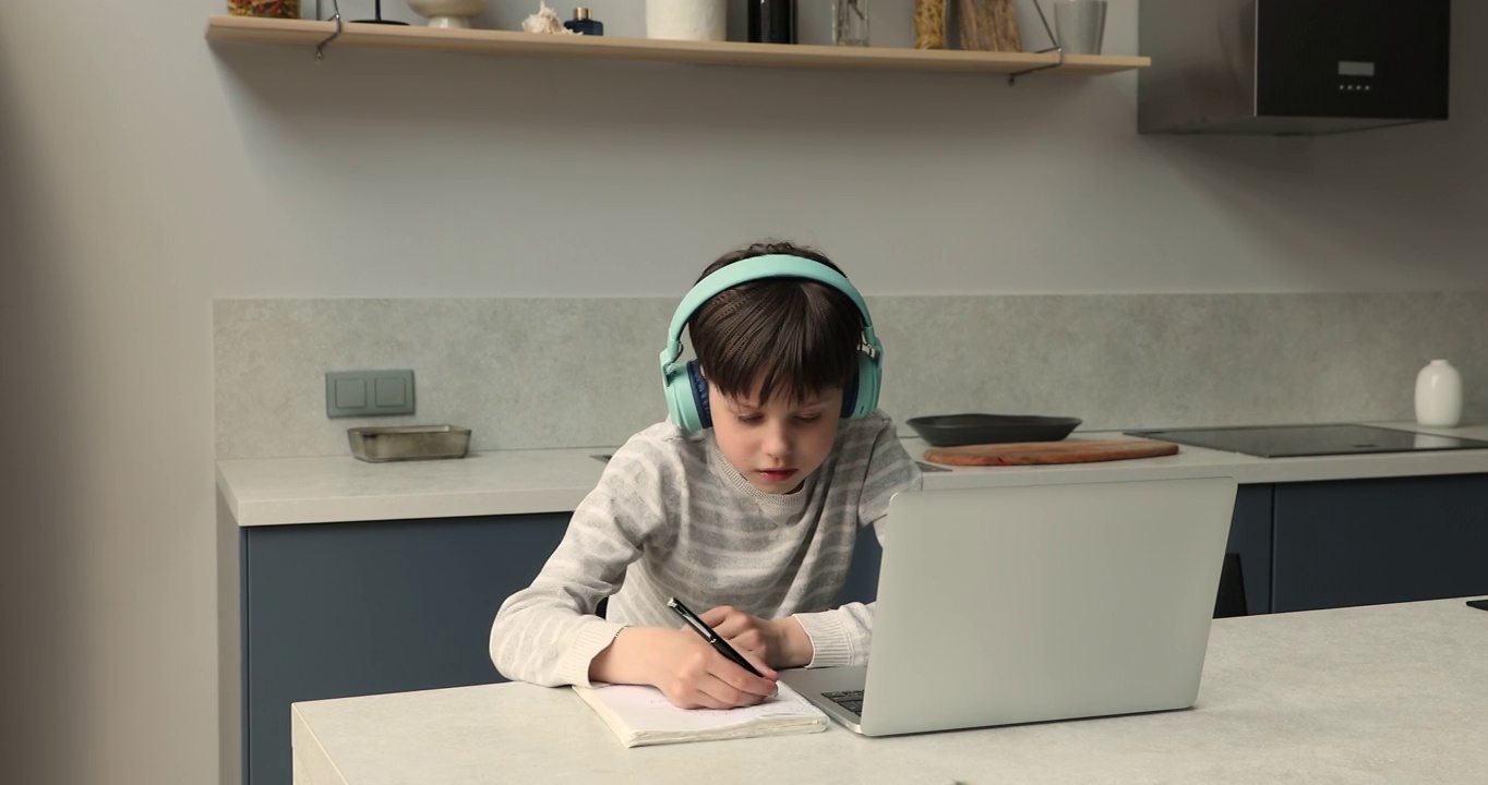一名男生戴着耳机在家用笔记本电脑上网学习视频素材