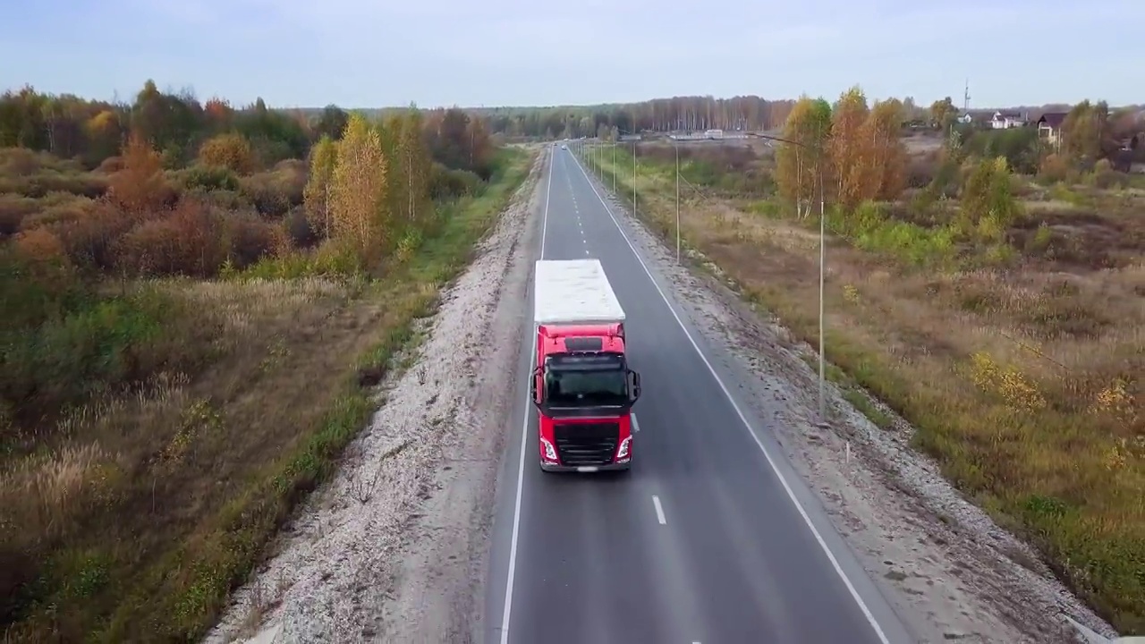 红色半挂车与拖车在高速公路上行驶的正面鸟瞰图。视频下载