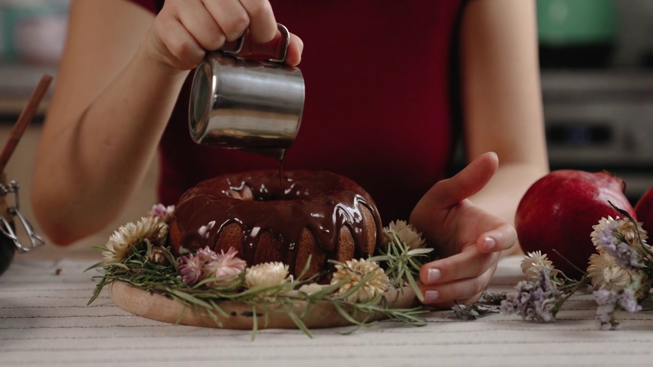 年轻的糖果师在厨房用巧克力装饰蛋糕视频素材