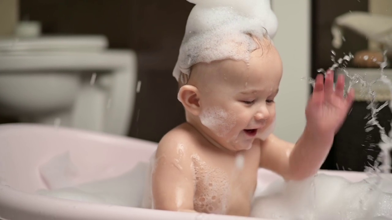 一个小男孩在泡泡浴里泼水。慢动作视频素材