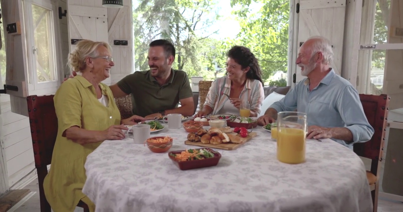 一对快乐的夫妇在餐厅吃早餐时和老夫妇交谈。视频素材