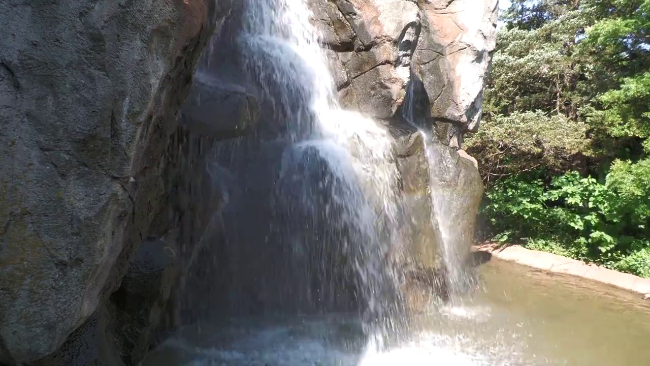 大岩石的下部，有水从顶部倾泻而下视频素材