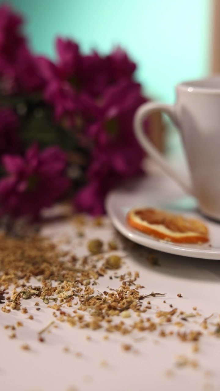 近距离观察桌子上的陶瓷茶杯，桌子上有草药，蜂蜜罐，鲜花视频下载