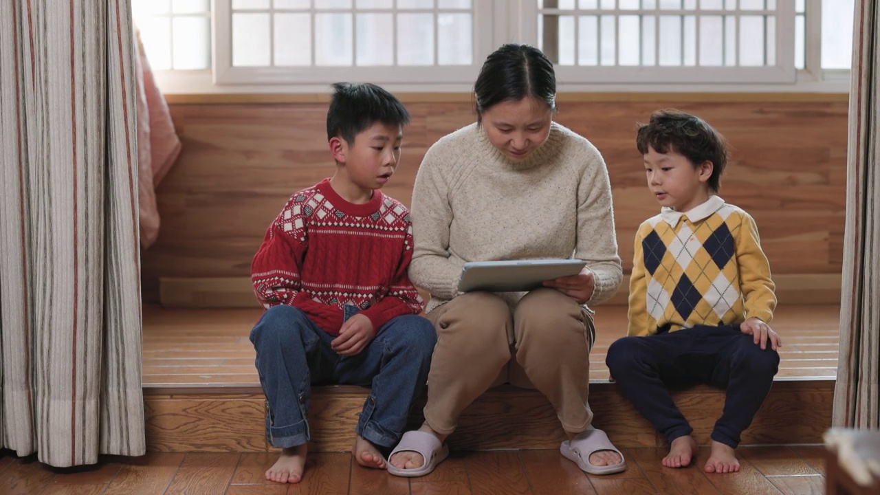 母亲和两个儿子在客厅玩平板电脑游戏视频素材