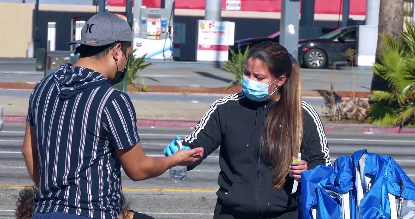 在加州洛杉矶的欧米克隆新冠肺炎大流行期间，年轻人在户外街道设施接受护士的冠状病毒Covid-19感染检测，4K视频下载