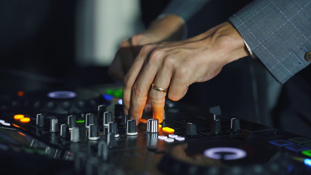 DJ的特写手微调DJ混音台上的各种轨道控制。视频素材