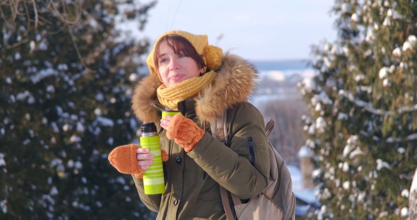 一个女人正在冬天的街道上喝视频下载