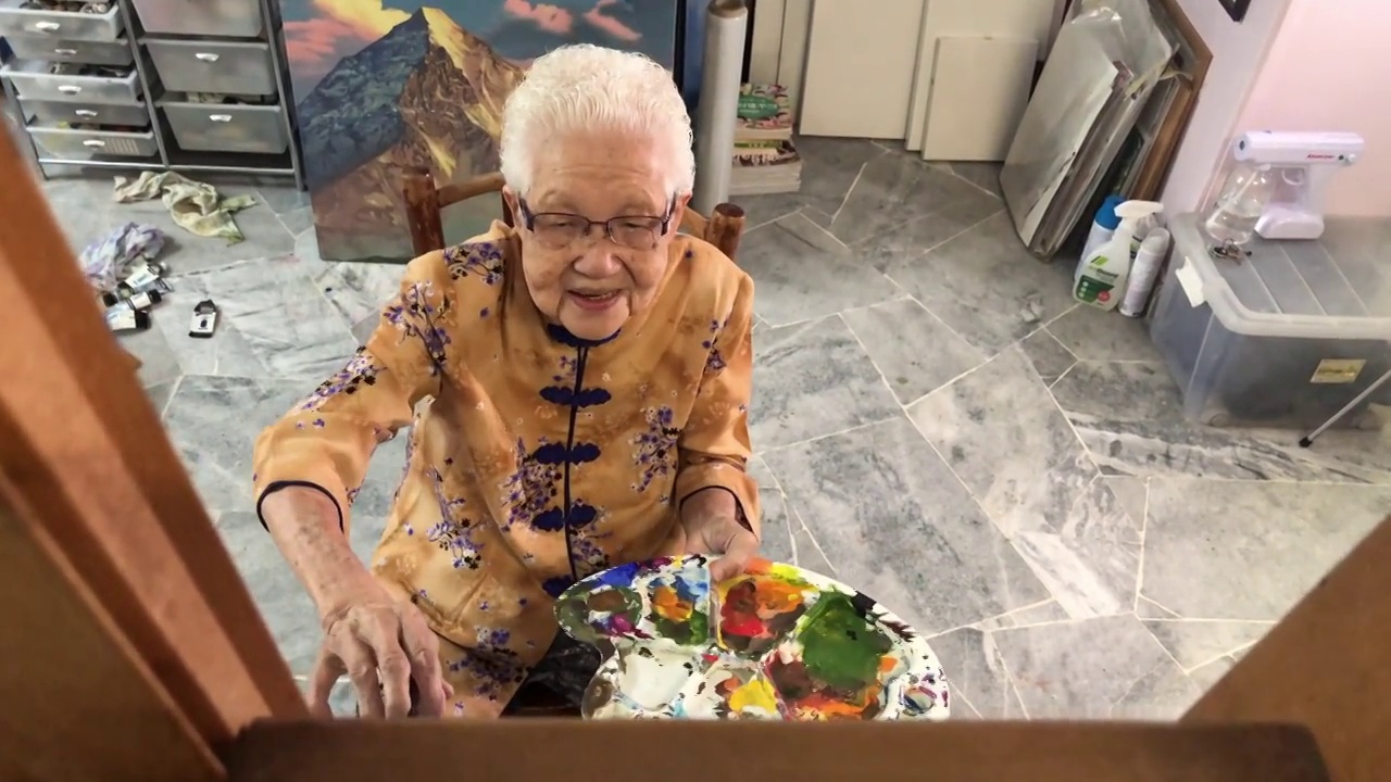 亚洲华人微笑的老年妇女在她的房子的画布上绘画视频下载