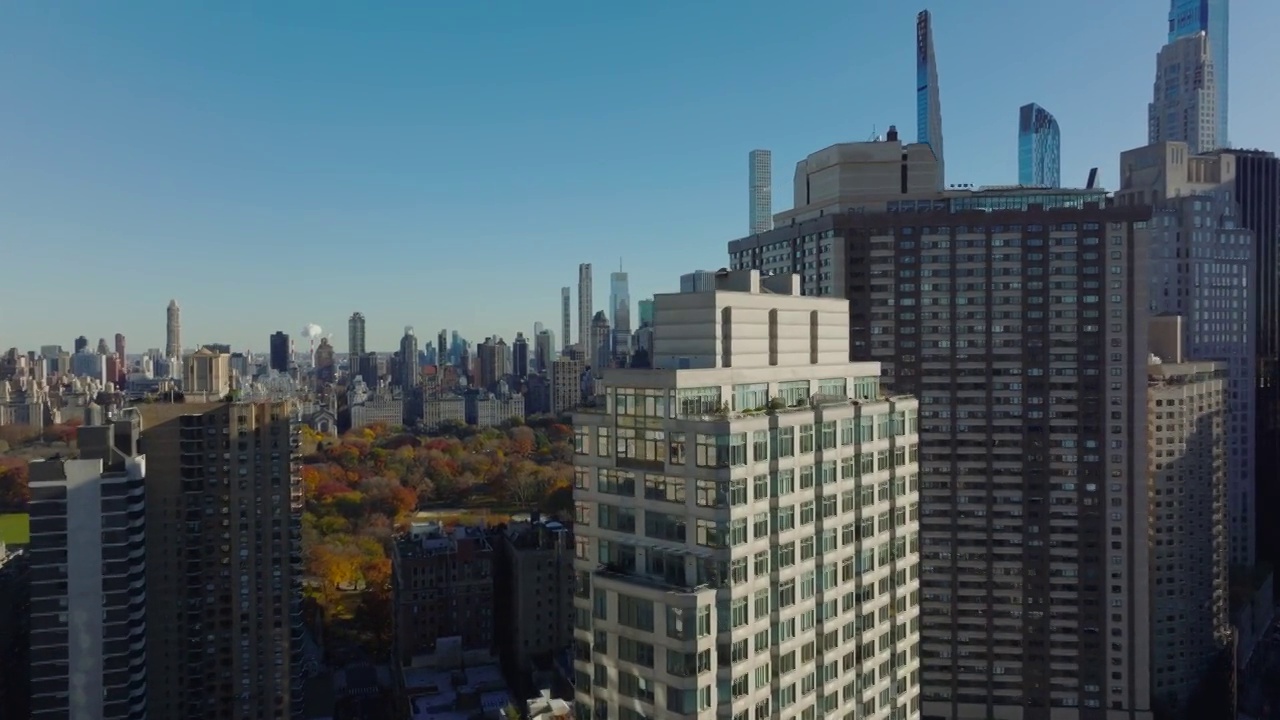 在高层建筑周围高架飞行。中央公园和周围的摩天大楼展现了多彩的秋天。曼哈顿，美国纽约市视频下载