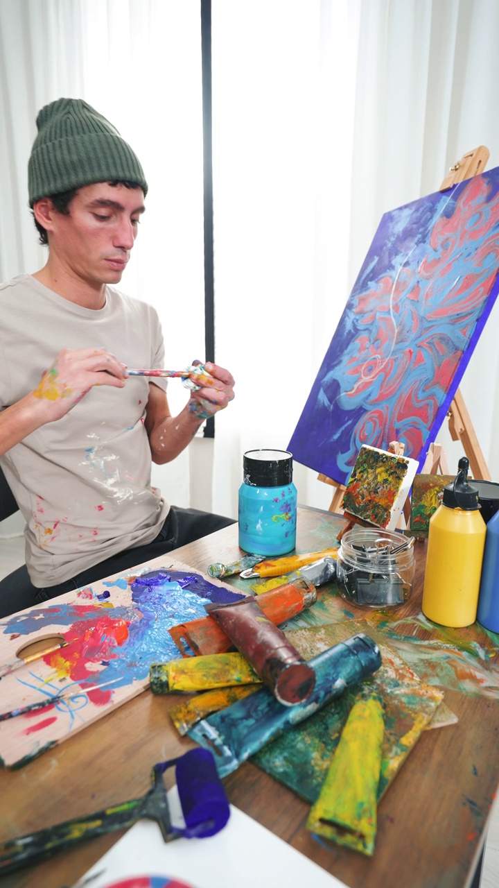 一个年轻的艺术家正在家里画一幅新的艺术品。视频下载