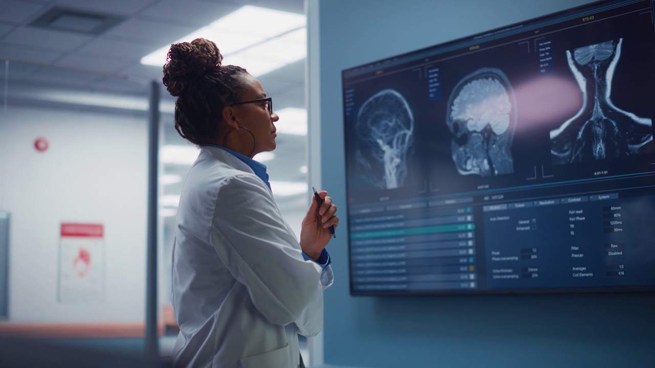 医学科学医院:自信的黑人女性神经学家，神经学家，神经外科医生，用MRI扫描看电视屏幕，思考病人的治疗方法。拯救生命视频素材