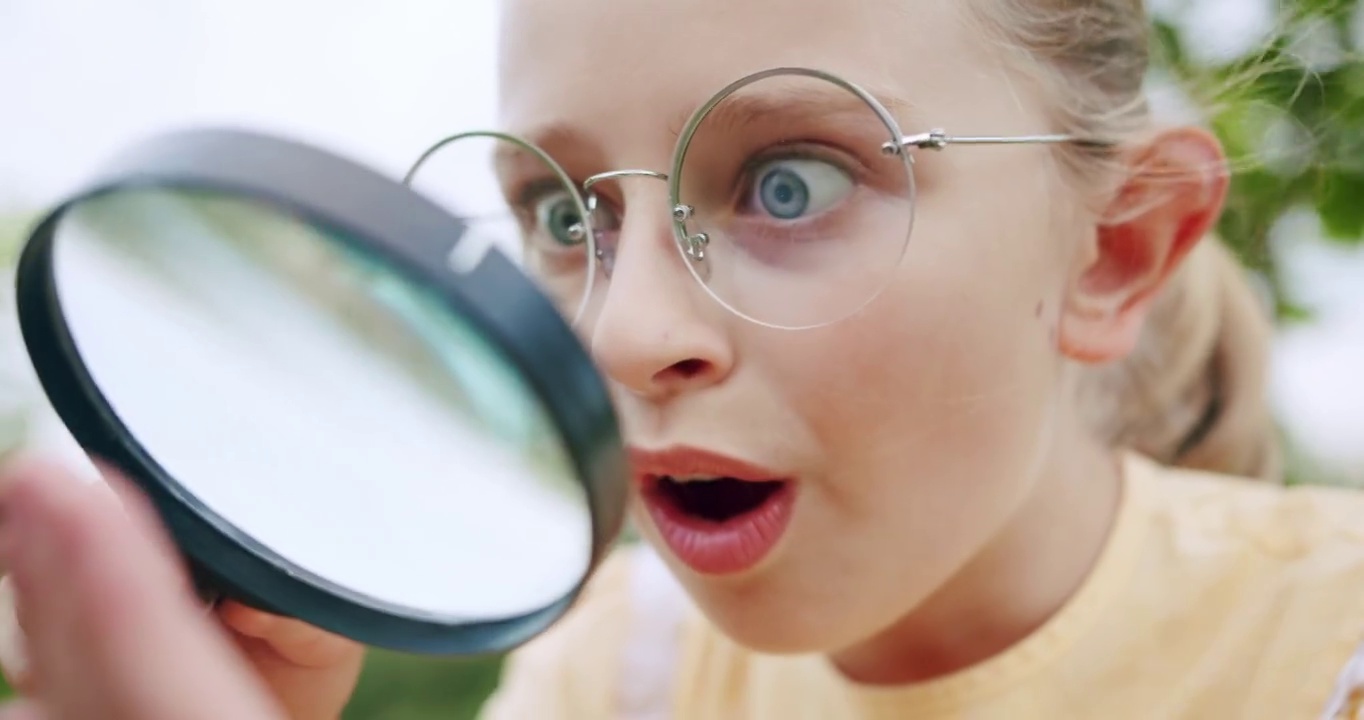 一个十几岁的女孩通过放大镜观察昆虫的微观世界。视频下载