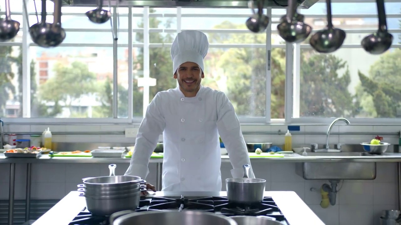 拉丁美洲厨师面带微笑，双手靠在炉子上视频素材